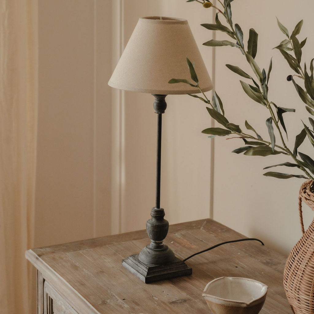 A wooden table lamp with a natural linen shade, placed on a wooden surface, with a simple classic style.