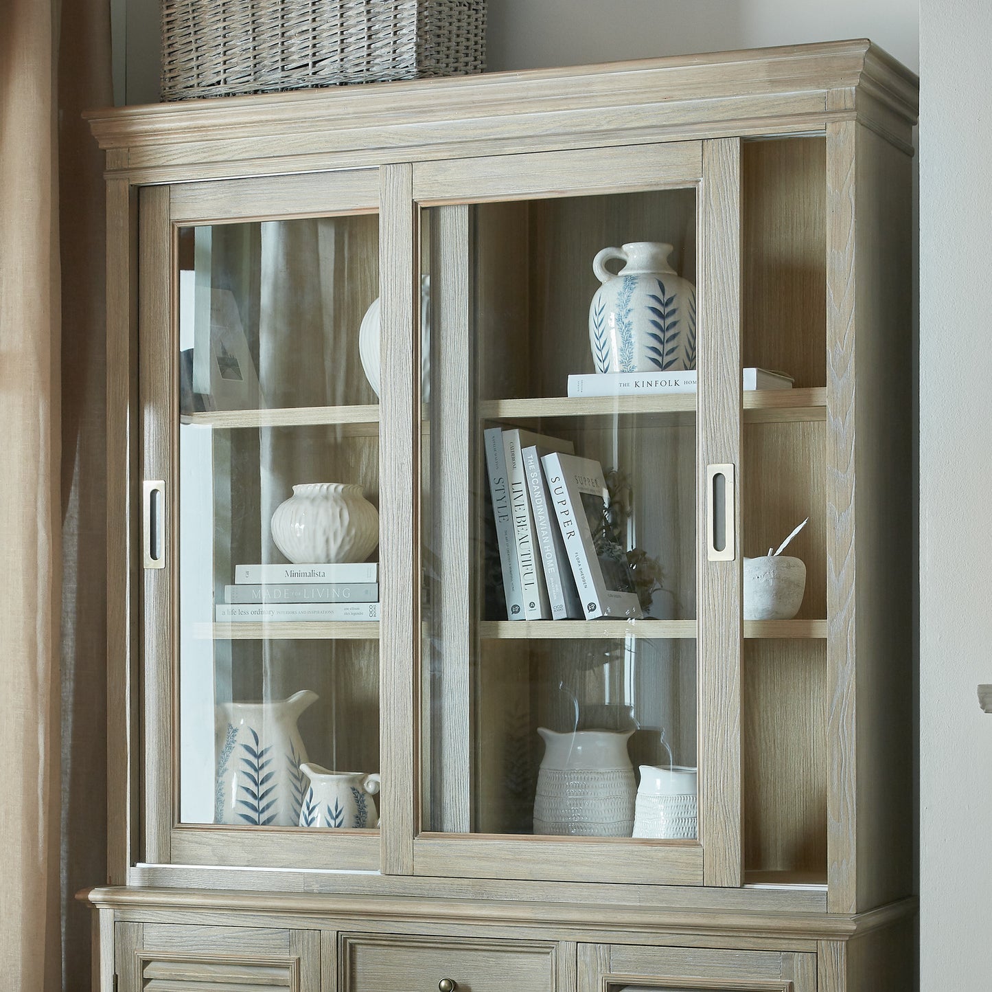 Wooden display cabinet with glass doors containing decorative items.