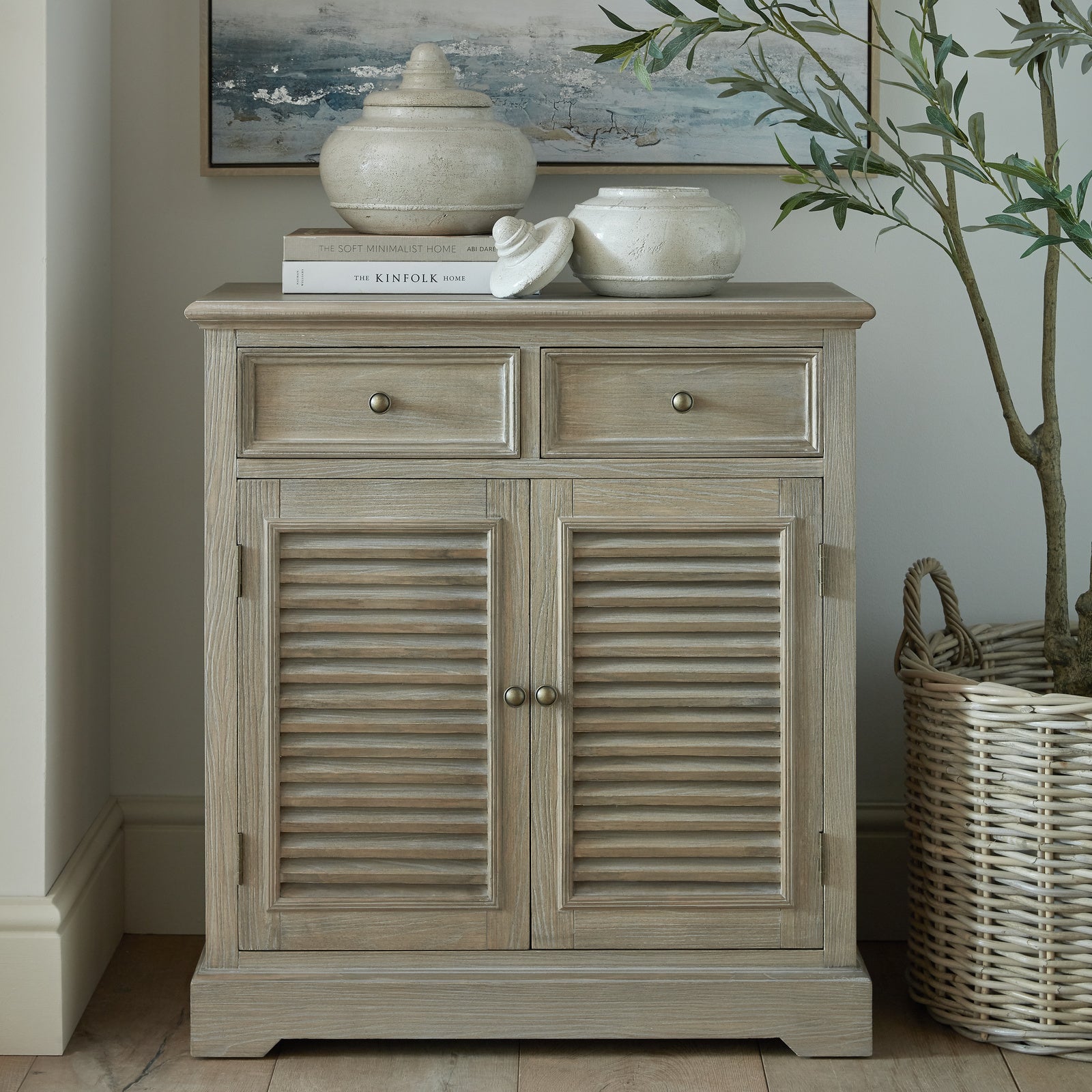 Wooden cabinet with louvered doors in a room setting with decor elements.