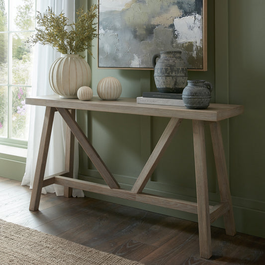 Wooden console table with decorative items against a green wall