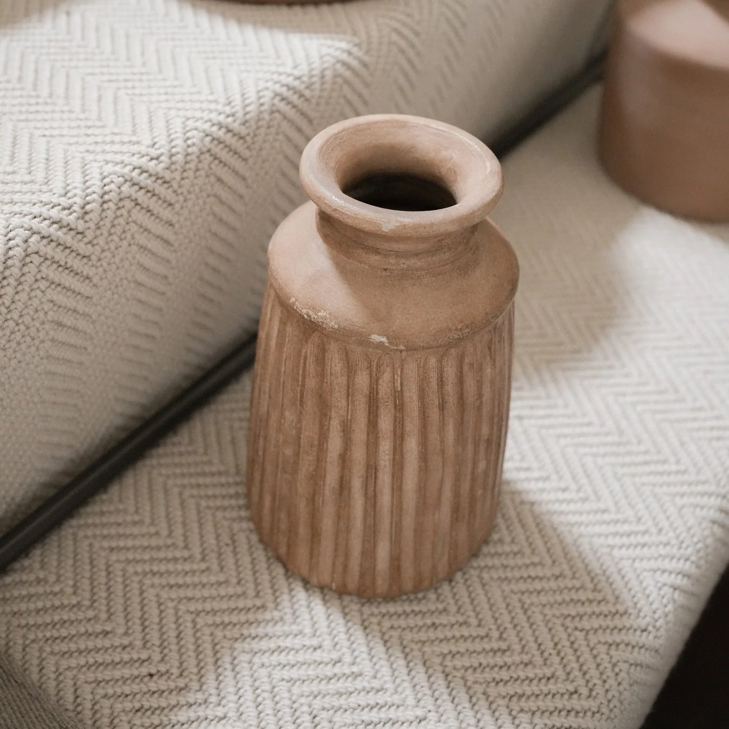 Terracotta vases on a textured surface with a mirror reflection.