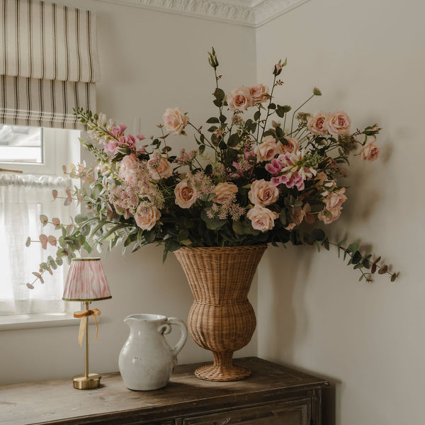 Large woven rattan urn vase filled with blush roses