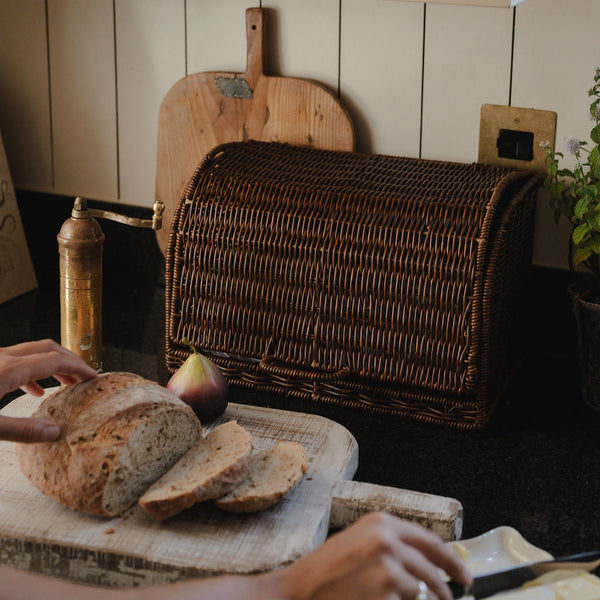 Ashford faux rattan bread basket on a kitchen worktop with bread being sliced