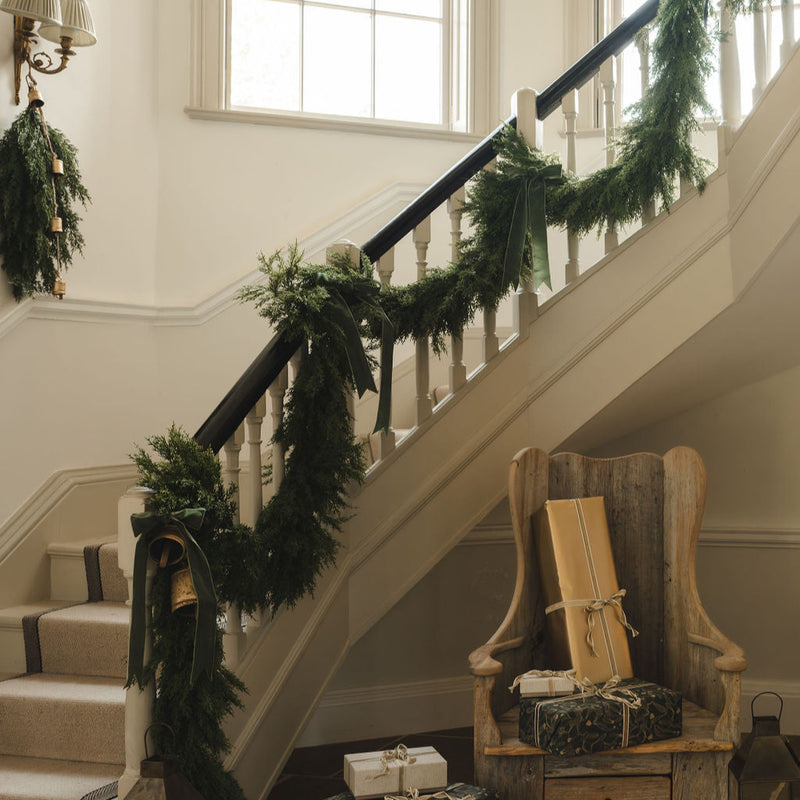 Cypress cedar garland dressed along a painted staircase with wrapped gifts below