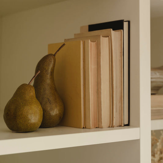 Ceramic pears styled on shelf with faux foliage and books