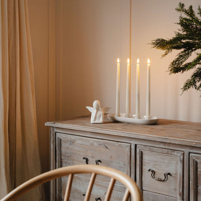 Wooden dresser with candles and a decorative angel on a neutral background
