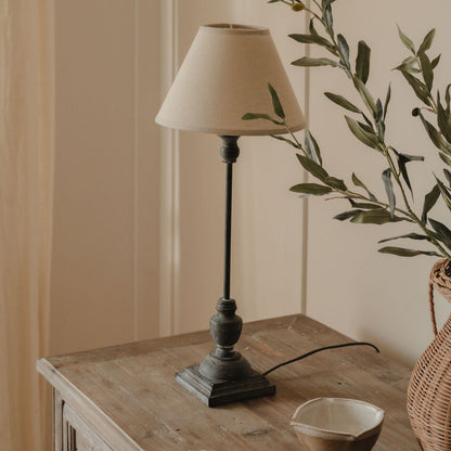 A wooden table lamp with a natural linen shade, placed on a wooden surface, with a simple classic style.